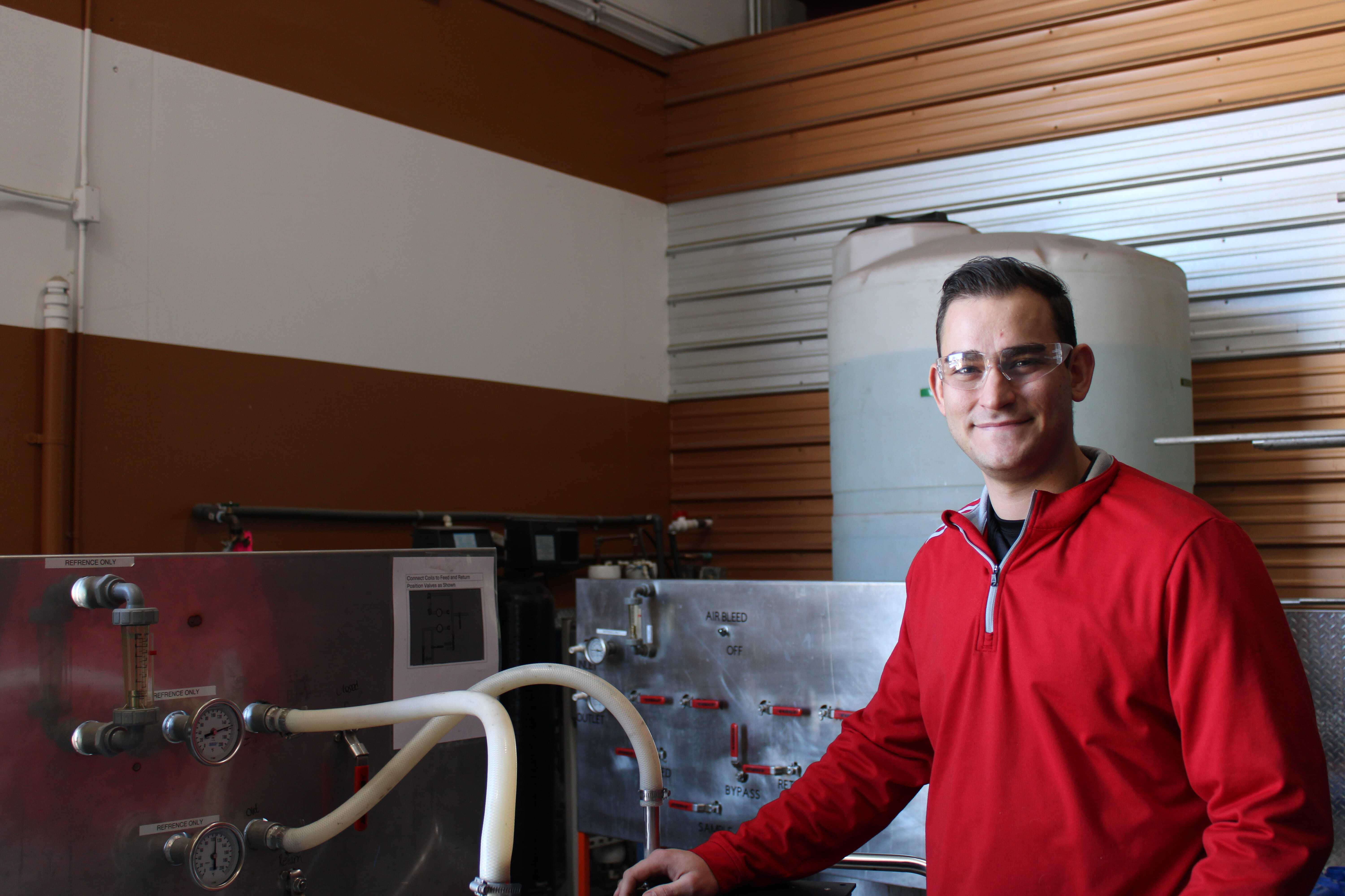 man in red sweater standing next to mechanical equipment