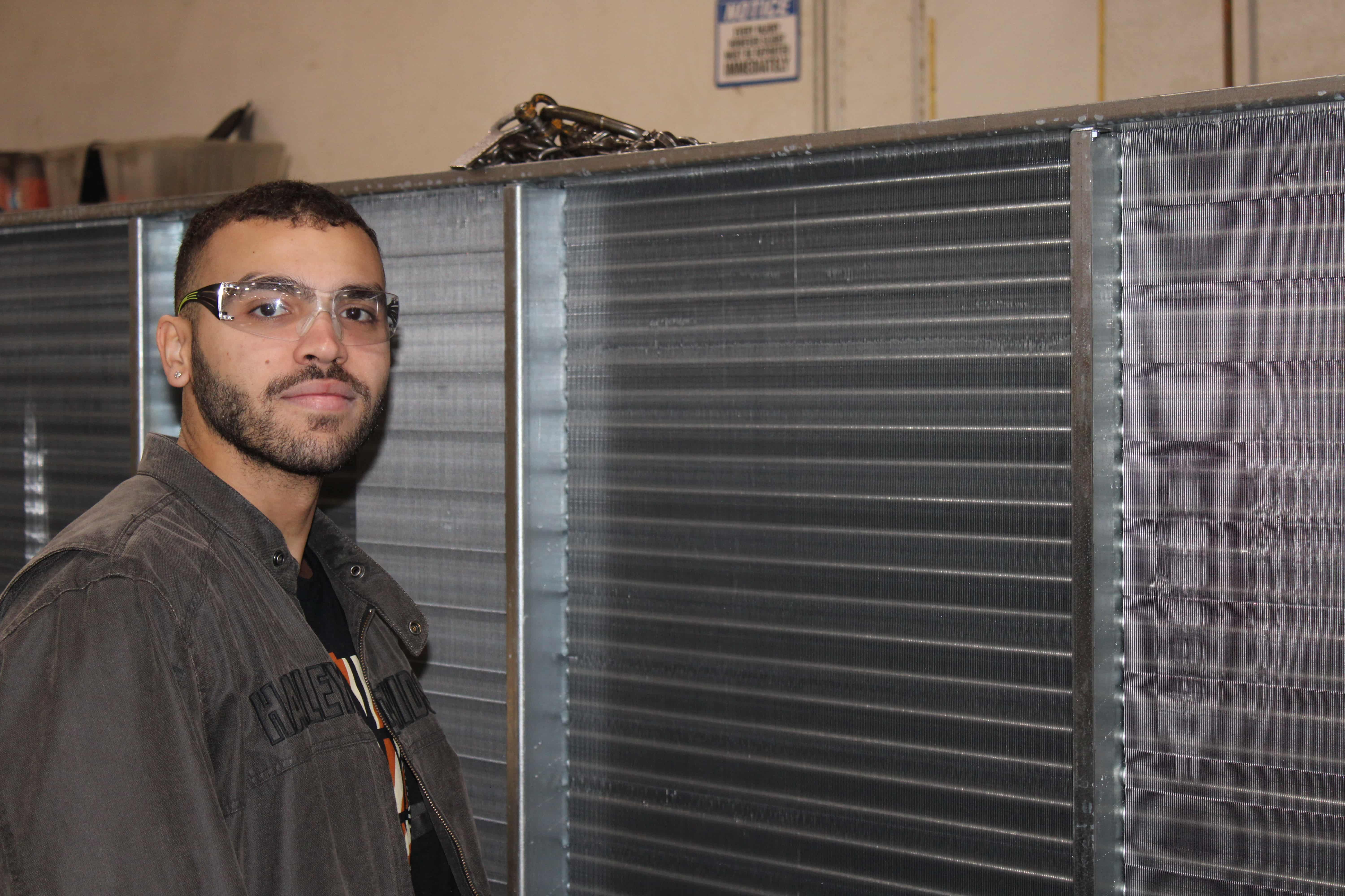 man in safety glasses next to heat exchanger